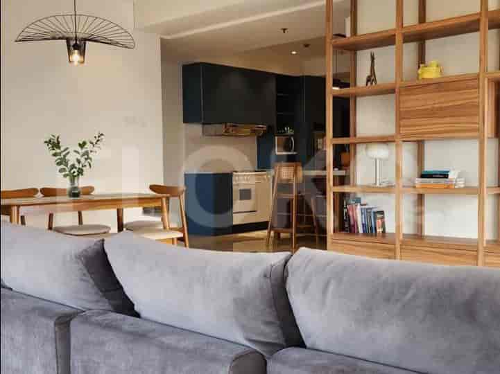 An open-plan living, dining, and kitchen area with a large grey sofa, dining table, and kitchen island.