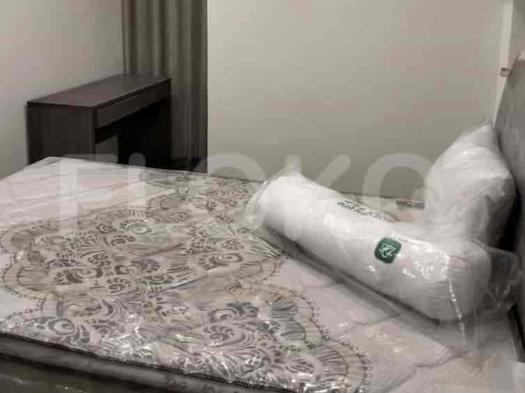 Kamar tidur dengan tempat tidur yang memiliki pelindung kasur dan bantal.