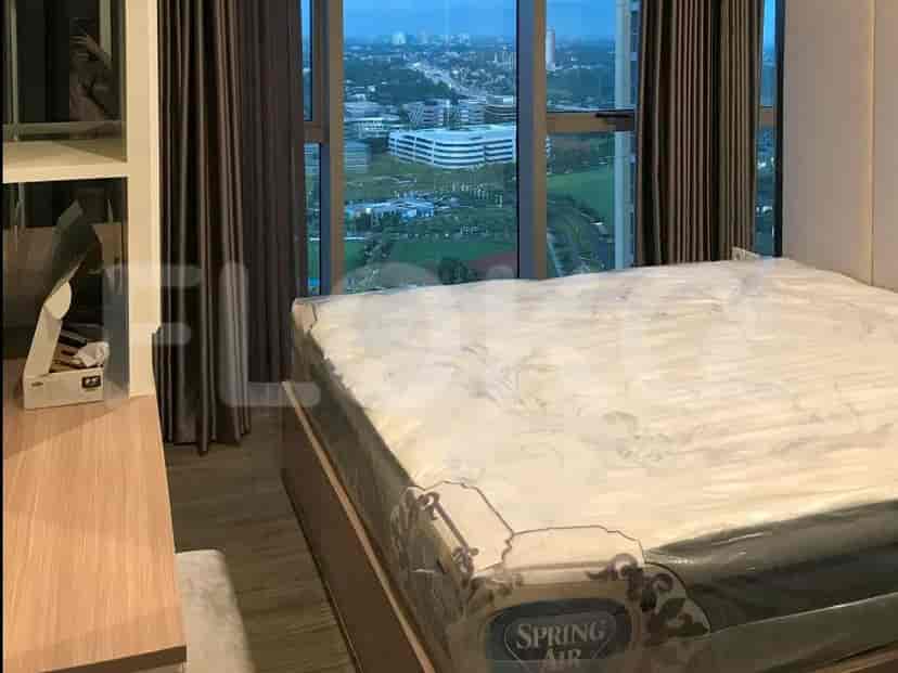 Sebuah kamar tidur dengan tempat tidur ukuran queen, kasur dalam plastik pelindung, dan jendela besar yang menawarkan pemandangan lanskap kota.