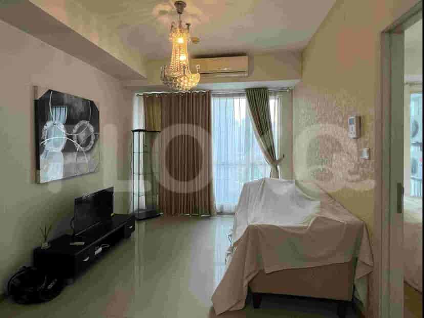 Sebuah ruang keluarga dengan sofa tertutup, meja TV dengan TV, dan lampu gantung dekoratif.
