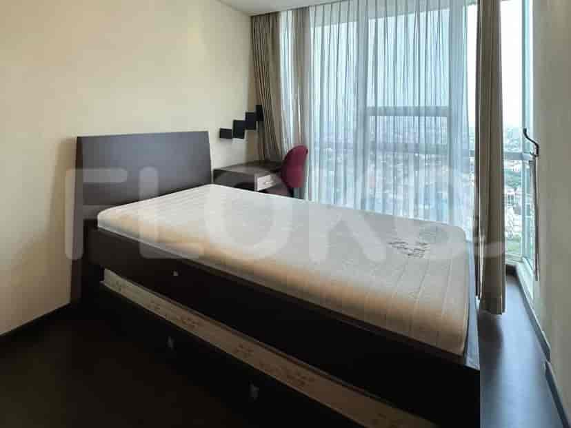 A bedroom with a twin bed, a desk, and a large window with curtains.