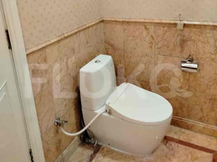 Kamar mandi dengan toilet dan dinding marmer.