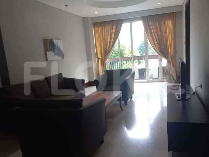 A spacious living room with an L-shaped grey sofa, wall-mounted smart TV, and large window with sheer curtains.