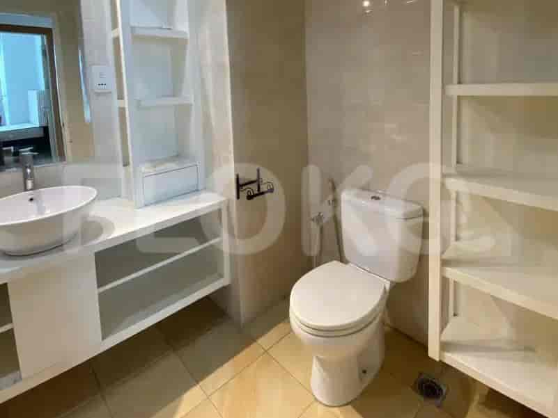 A bright bathroom with a toilet, sink, and shelves.