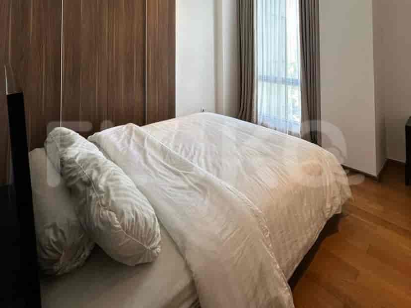 A bedroom with a large bed, wooden wardrobe, and window with curtains.