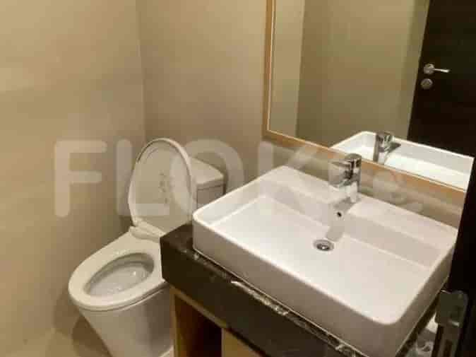 A bathroom with a toilet, sink, and mirror.