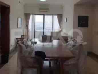 A dining room with a large wooden table and chairs covered in plastic.