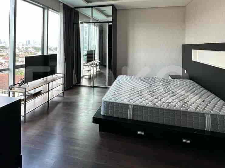 A minimalist bedroom with a queen-size bed, a dark wooden platform base, a mounted headboard, and a TV console.