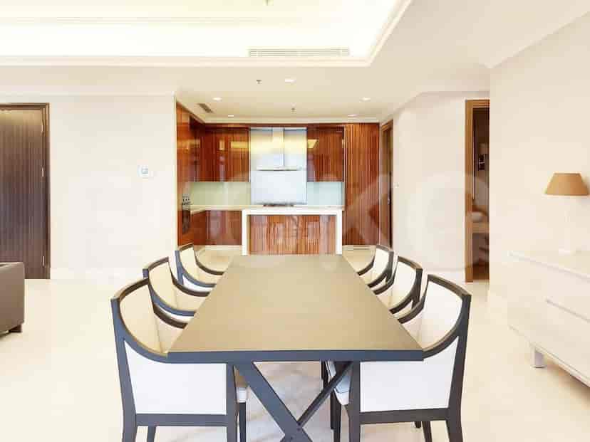 An open-plan kitchen and dining area, with a long dining table and wooden cabinetry.