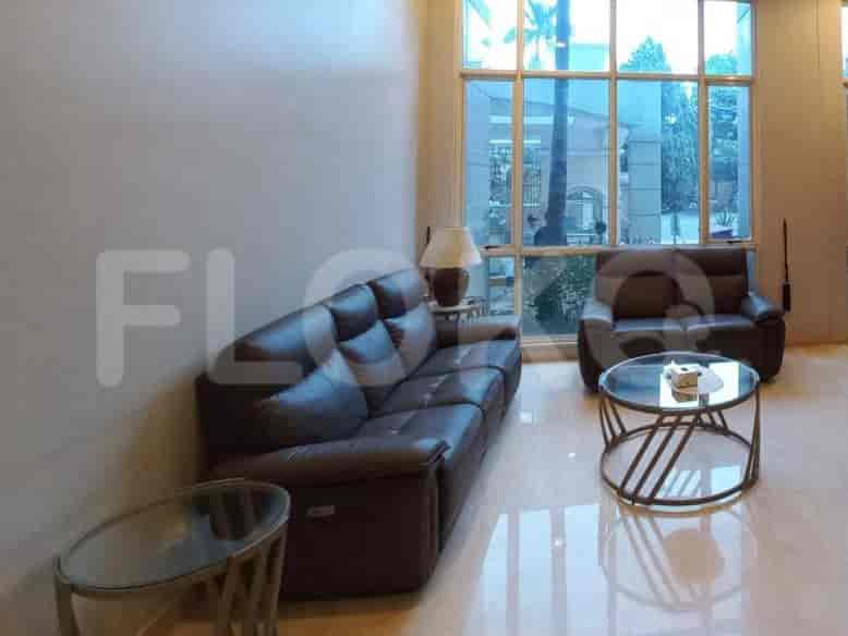 A spacious living room with a dark brown leather sofa, a matching armchair, and a glass coffee table.