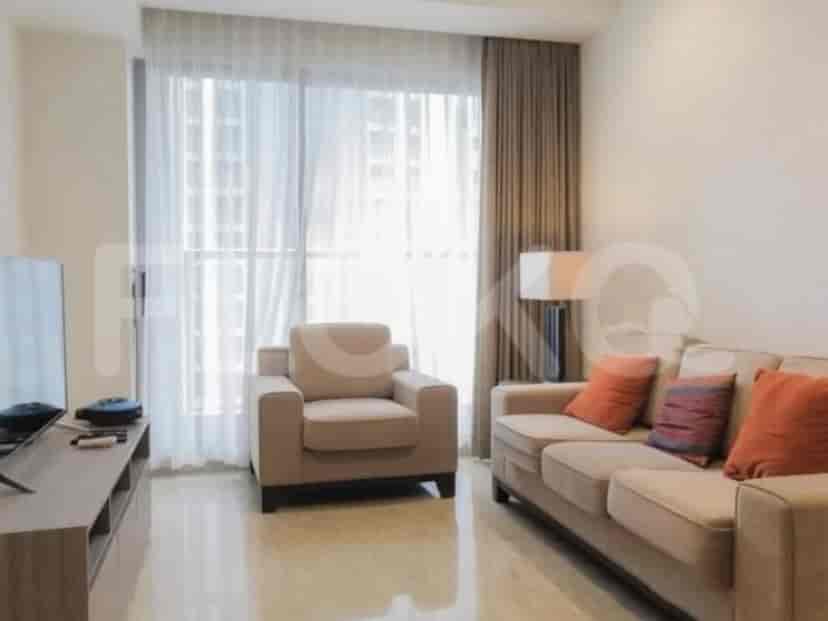 Sebuah ruang tamu dengan sofa, kursi berlengan, dan konsol TV.