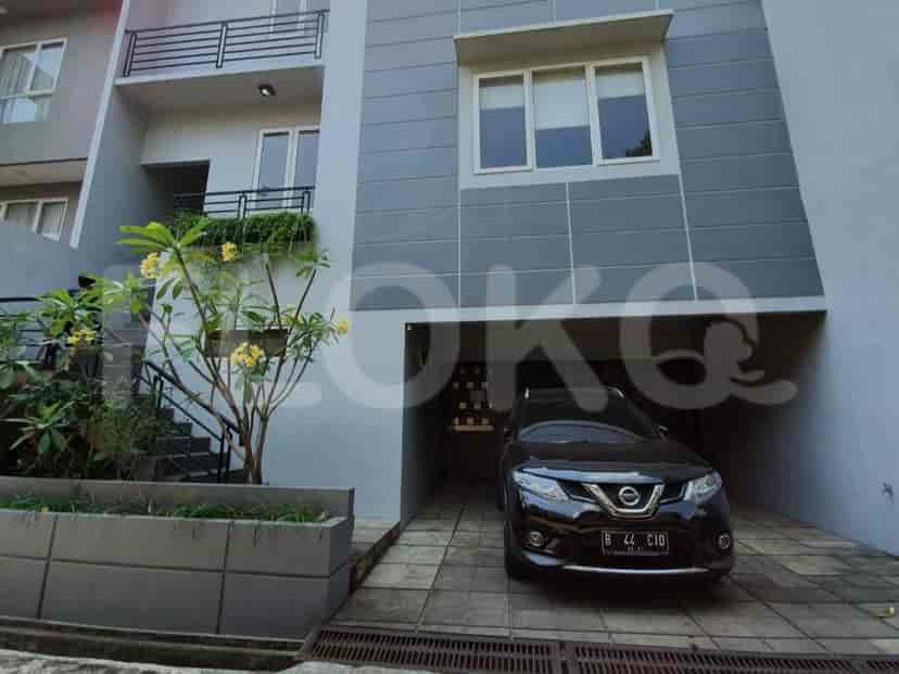 Bagian luar depan townhouse abu-abu modern dengan Nissan X-Trail hitam yang terparkir di carport.