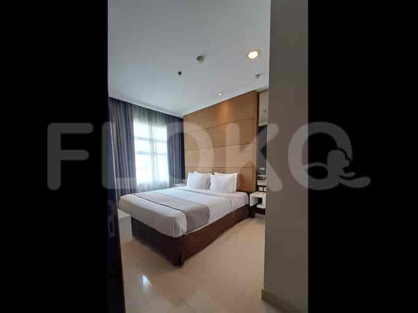 A bedroom with a queen-sized bed, bedside tables, and a large headboard.