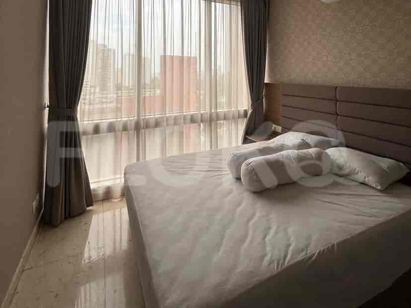 A bedroom with a large bed, window, and sheer curtains.