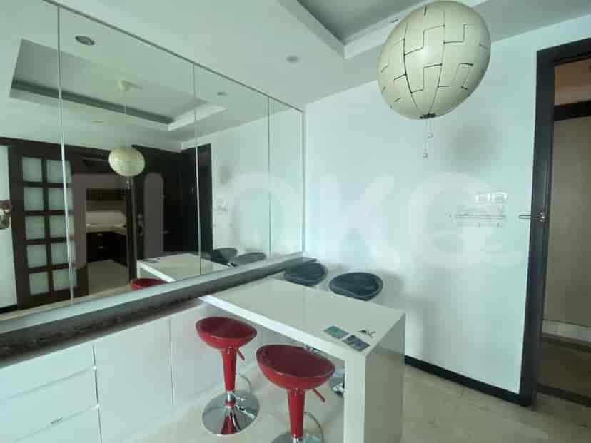 A kitchen island with red stools and a large mirror reflecting the room.