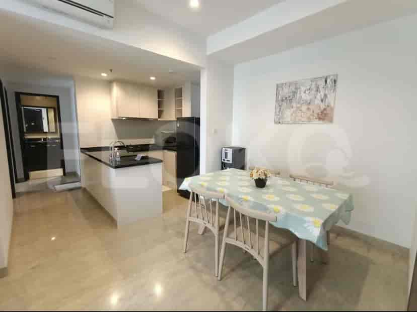 A modern kitchen with white cabinets, black countertops, and a dining area with a table and chairs.