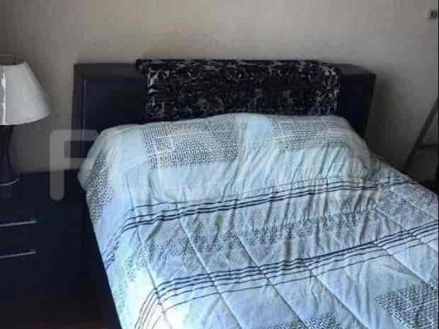 Bedroom with a bed, nightstand, lamp, and patterned bedspread.