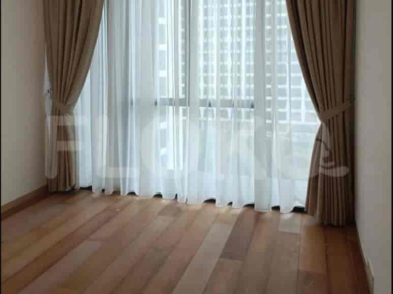 Area kamar tidur dengan lantai kayu ringan dan jendela besar.