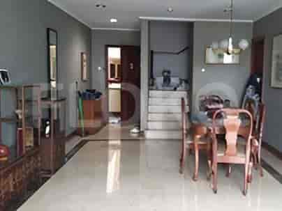 A spacious living and dining area with tiled floors, a wooden cabinet, a dining set, and stairs leading to another level.