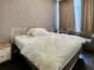 A bedroom with a large bed, bedside table, and curtains.