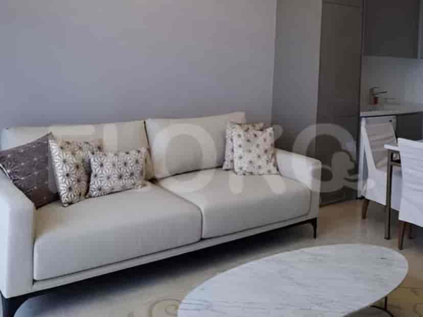 Sebuah ruang tamu modern yang menampilkan sofa berwarna terang, meja kopi berdaun marmer, dan area dapur terbuka.