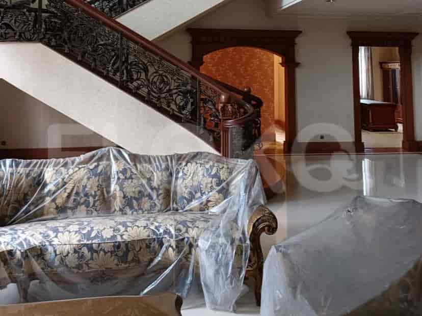 A living room featuring a sofa covered in plastic, a staircase, and doorways leading to other rooms.
