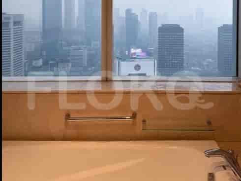 A bathroom with a bathtub and city view.