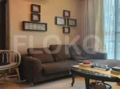 A living room with a brown sofa, framed art, and wooden furniture.