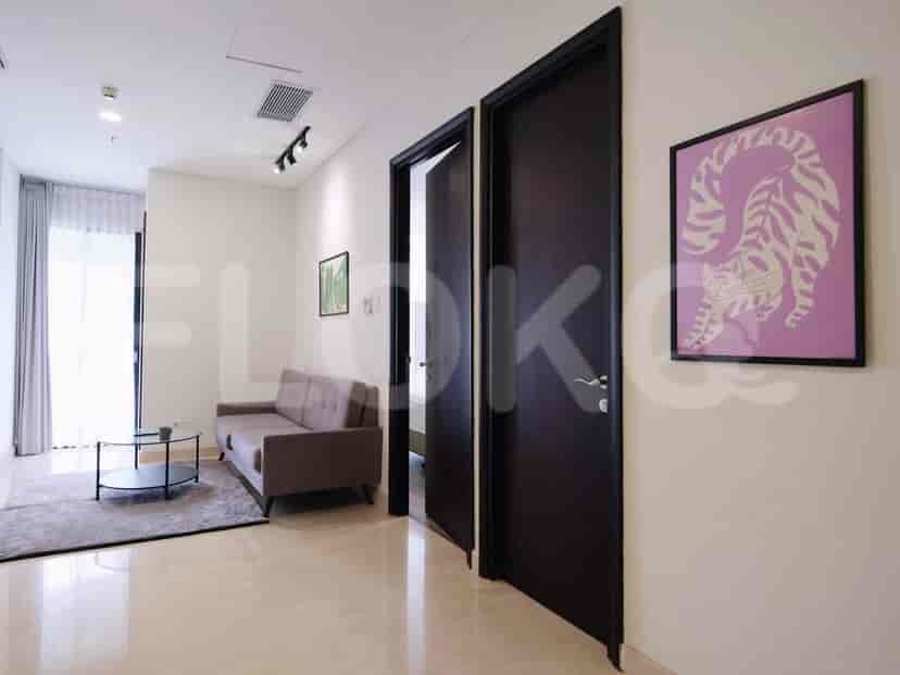 A hallway with dark doors, leading to rooms, with artwork on the walls.