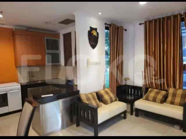 An open kitchen with a stainless steel island and a seating area with two small sofas.