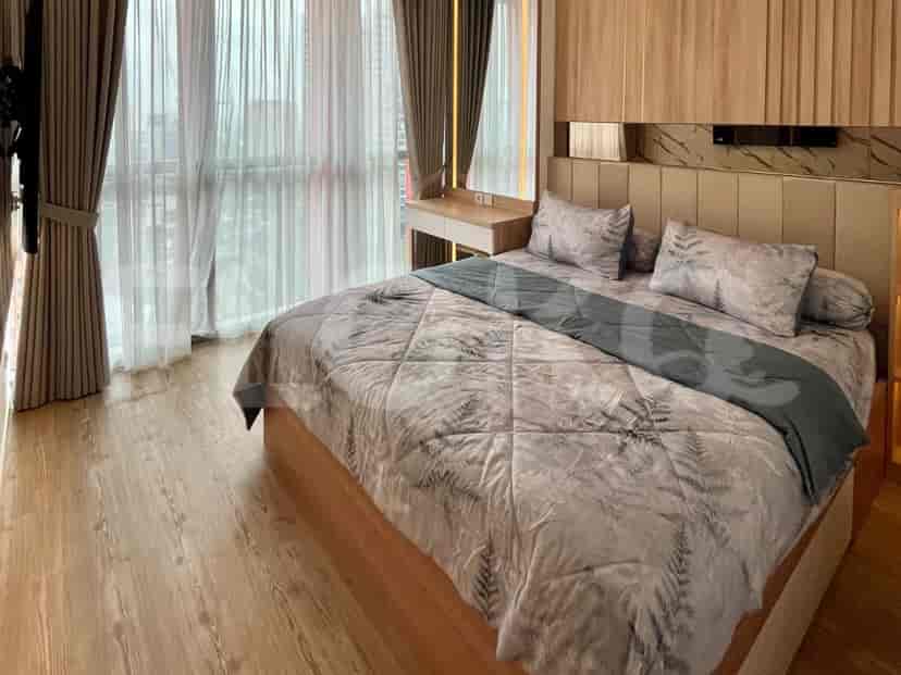 A well-lit bedroom with a large bed, wooden flooring, and city view.