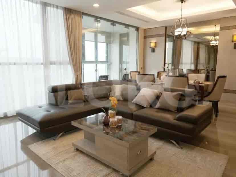 A modern living room featuring a large dark leather sectional sofa, a marble-top coffee table, and floor-to-ceiling windows with sheer curtains.