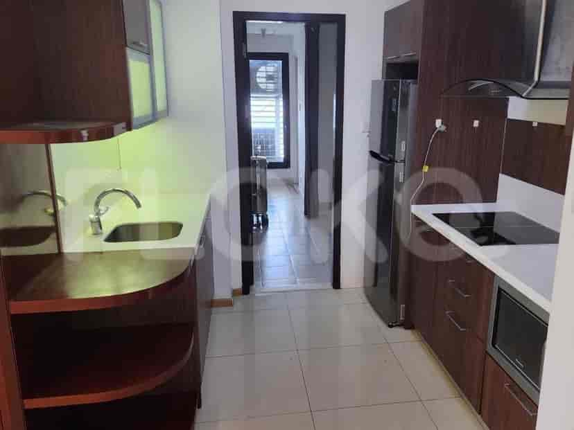 Dapur modern dengan lemari kayu gelap, meja dapur putih, kulkas stainless steel, dan kompor listrik.