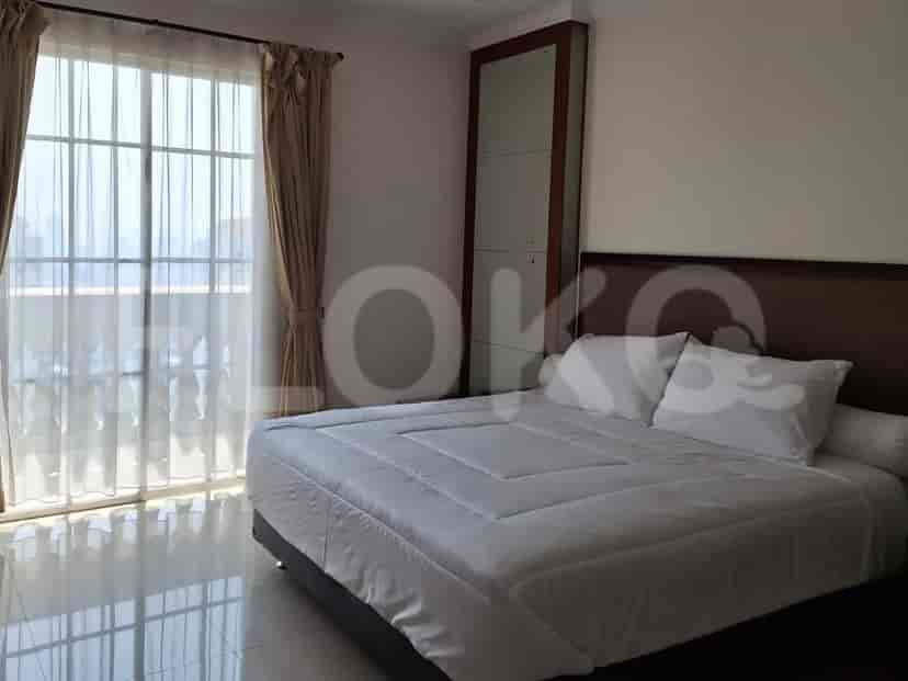 Kamar tidur dengan tempat tidur ukuran king, jendela besar dengan tirai tipis, dan balkon terlihat di luar.