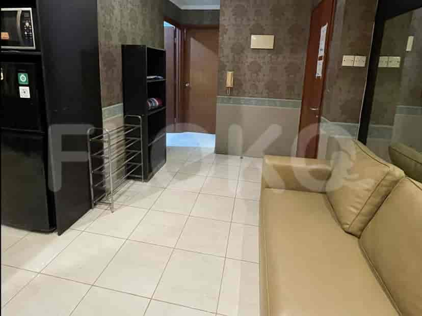 A living area with a sofa, refrigerator, shoe rack, and a black shelf unit.