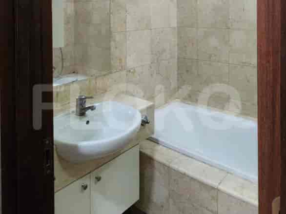 Kamar mandi dengan dinding berubin krem, wastafel putih, dan bak mandi.