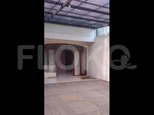 Exterior view of a covered patio or entrance with tiled flooring and wooden door.