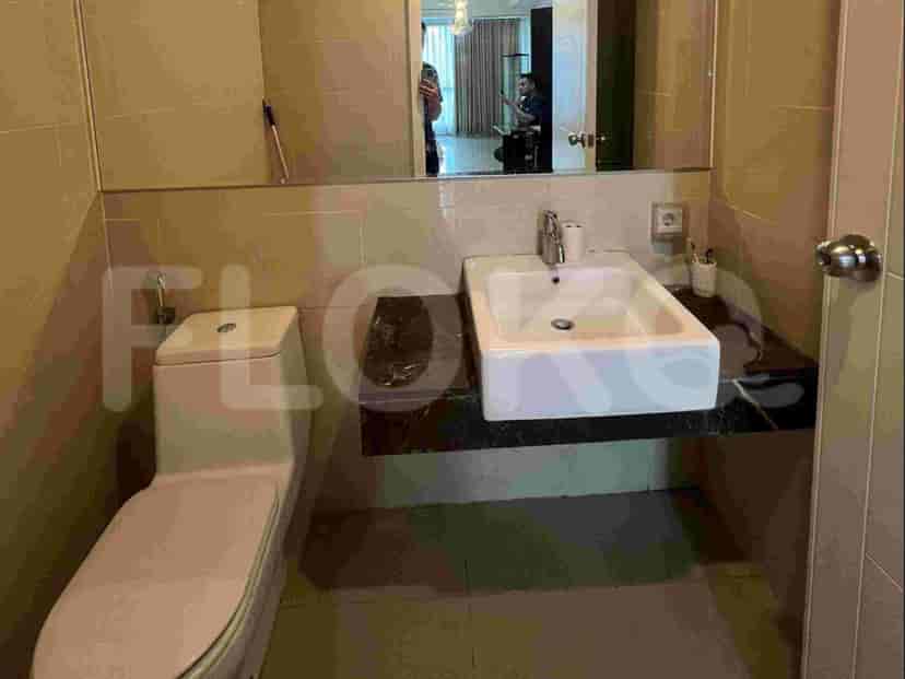 Sebuah kamar mandi dengan toilet dan wastafel dengan cermin besar di atasnya.