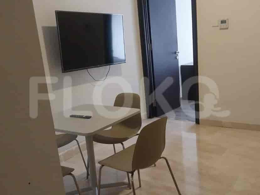 A compact dining area with a small white table and three chairs, with a TV mounted on the wall above.