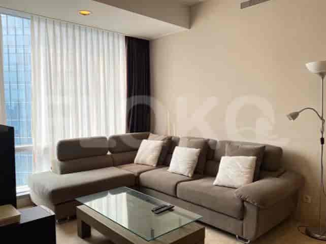 A modern living room with a sectional sofa, glass coffee table, and large windows.