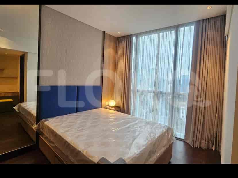 A bedroom with a bed, bedside table, and large windows.