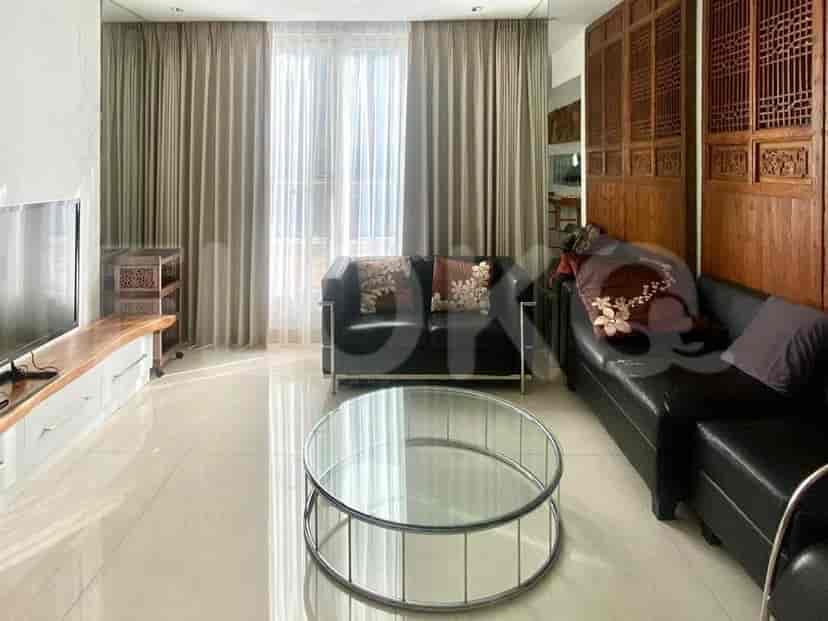 Bright living room with black leather sofas, a glass coffee table, and sheer curtains.