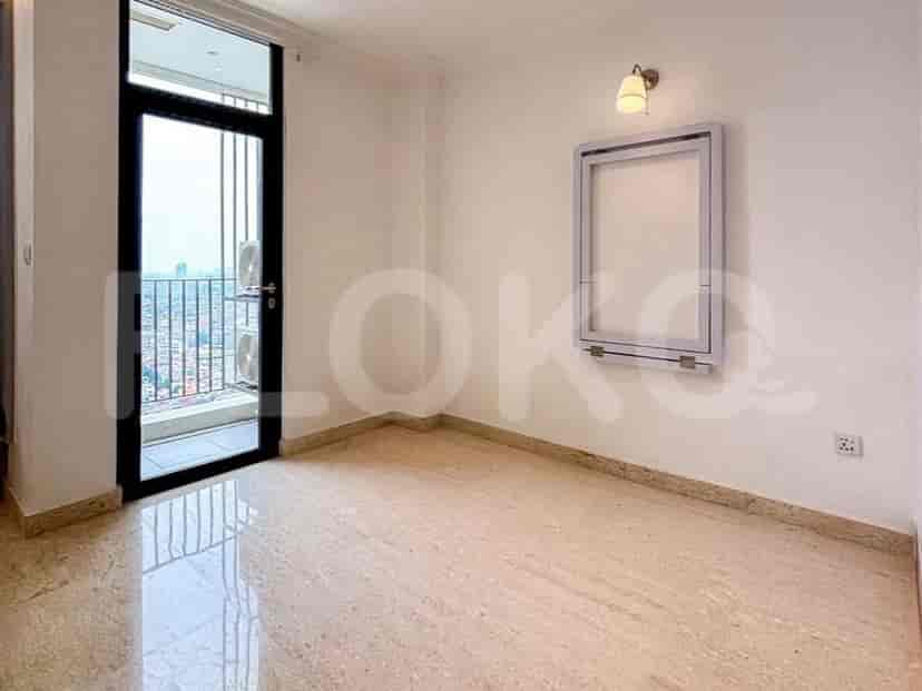 Empty bedroom with a door leading to a balcony, a folding table, and a wall light.