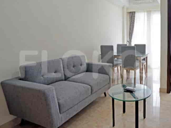 A living room with a grey sofa, a glass coffee table, and a dining table with chairs.