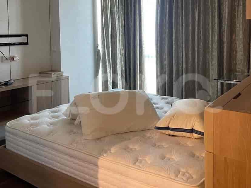 A well-lit bedroom with a double bed, bedside cabinets, and sheer curtains.