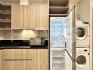 A modern kitchen with wooden cabinets, a refrigerator, and laundry appliances.