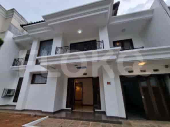A two-story house with a white facade, balcony, and open door.