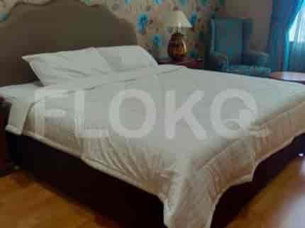 A bedroom with a large white comforter on the bed and a blue armchair in the corner.