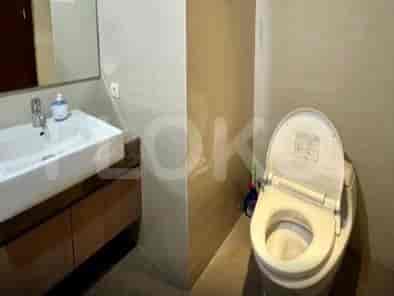 A bathroom with a toilet, sink, and wooden vanity.