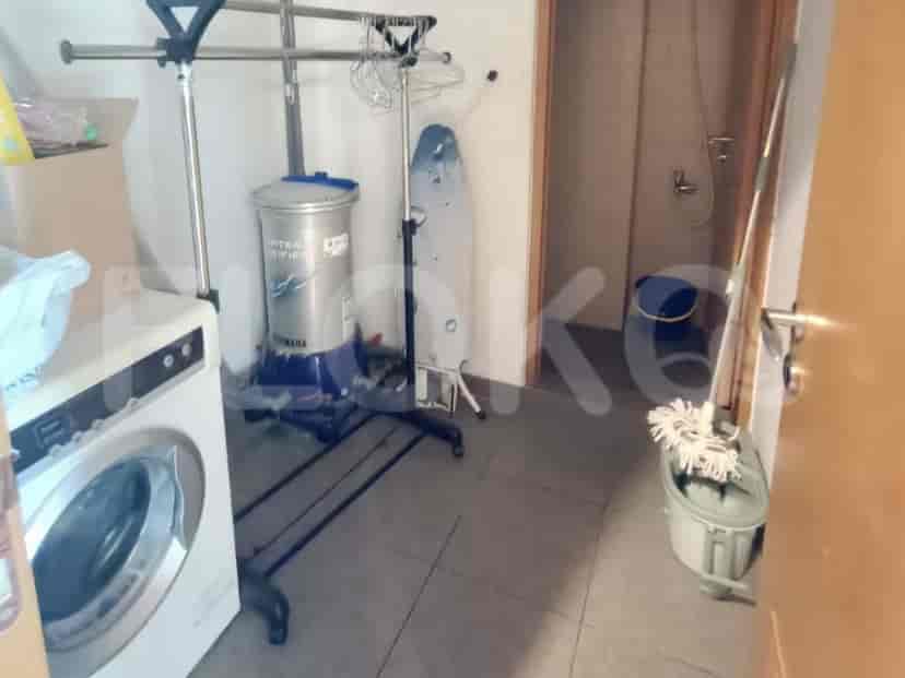 Ruang utilitas dengan mesin cuci, rak pengering, dan perlengkapan pembersih.